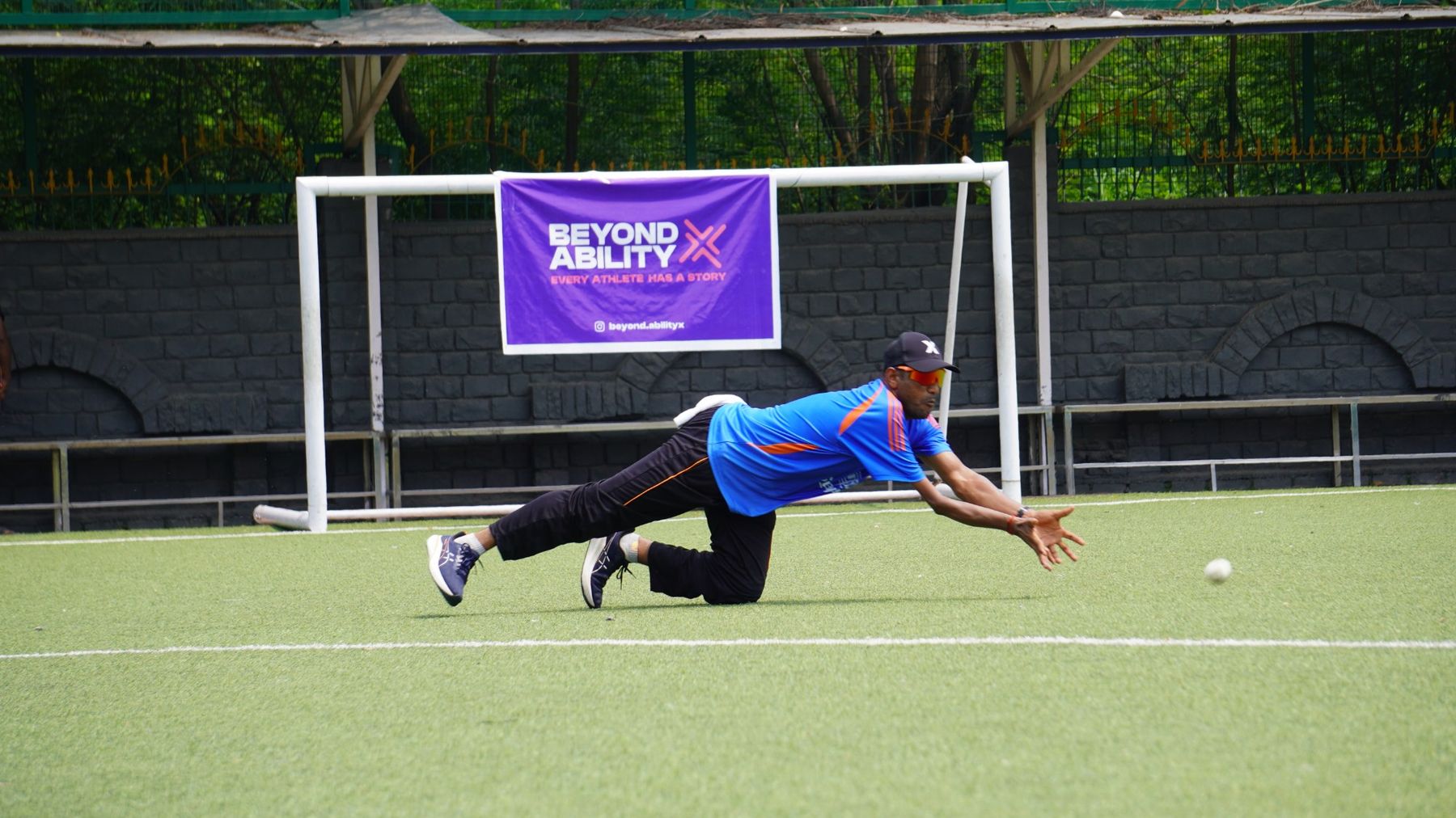 A BAX athlete diving for a catch in front of a Beyond Ability X banner